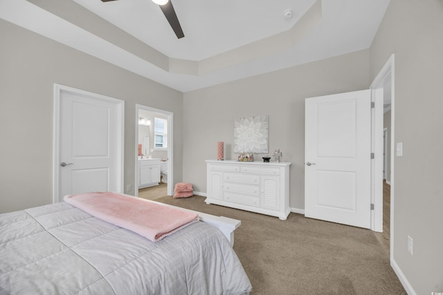 bedroom with ensuite bath, light colored carpet, a raised ceiling, and ceiling fan