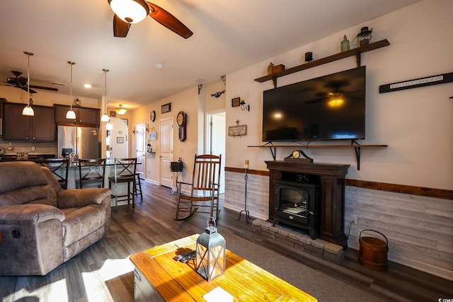 living room with dark hardwood / wood-style floors, a wood stove, and ceiling fan