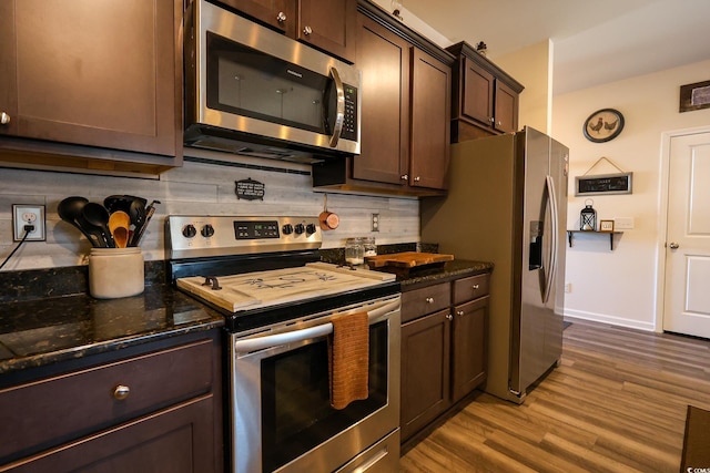 kitchen featuring dark stone countertops, dark brown cabinets, stainless steel appliances, and wood-type flooring