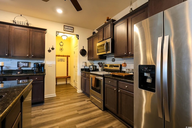 kitchen with stainless steel appliances, light hardwood / wood-style flooring, decorative backsplash, and dark stone counters