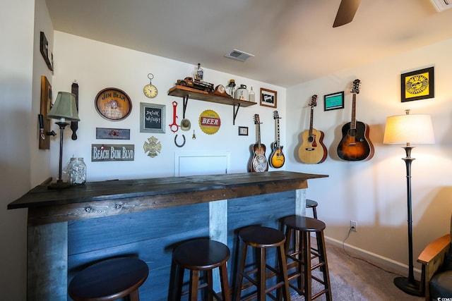 bar featuring ceiling fan and dark carpet