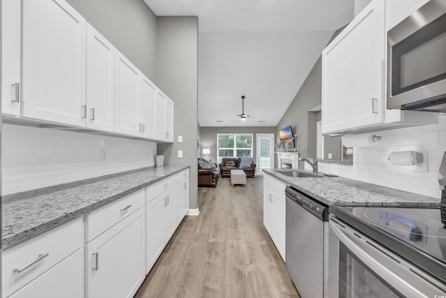 kitchen with light stone counters, stainless steel appliances, and white cabinets