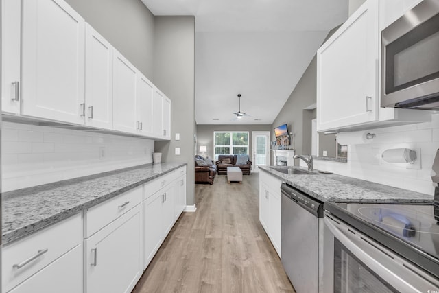 kitchen with stainless steel appliances, light wood-style floors, a sink, a ceiling fan, and white cabinetry