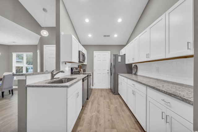 kitchen with appliances with stainless steel finishes, a sink, decorative backsplash, white cabinets, and high vaulted ceiling