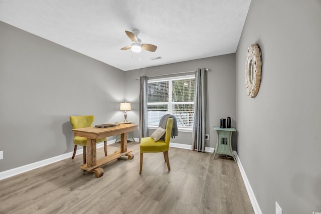 home office with ceiling fan, wood finished floors, baseboards, and a textured ceiling