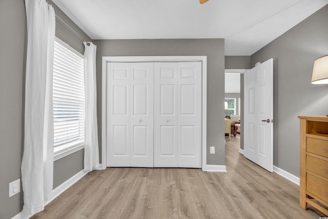 unfurnished bedroom featuring light wood-style flooring, a closet, and baseboards