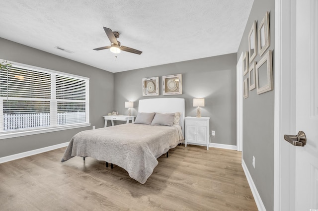bedroom featuring light wood-style floors, baseboards, a textured ceiling, and ceiling fan