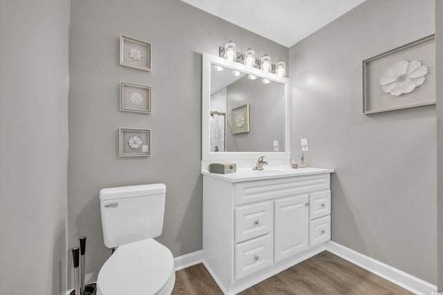 bathroom with wood finished floors, toilet, baseboards, and vanity