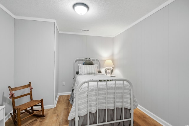 bedroom with hardwood / wood-style floors, crown molding, and a textured ceiling