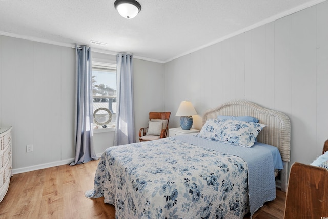 bedroom featuring hardwood / wood-style flooring, a textured ceiling, and ornamental molding