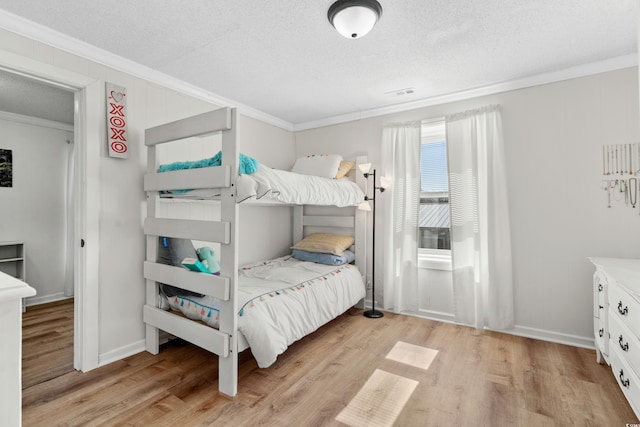 bedroom featuring a textured ceiling, crown molding, and light wood-type flooring