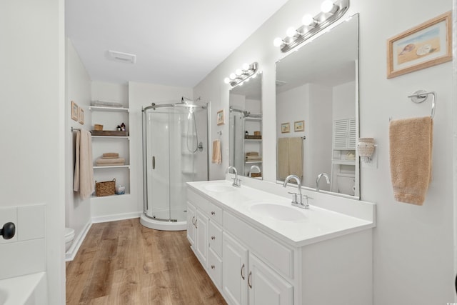 bathroom featuring wood-type flooring, toilet, a shower with shower door, and vanity