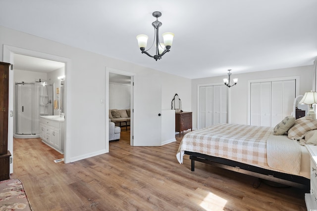 bedroom with two closets, sink, light hardwood / wood-style flooring, an inviting chandelier, and connected bathroom