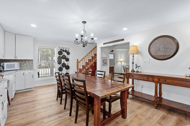 dining area featuring light hardwood / wood-style floors, an inviting chandelier, and ornamental molding