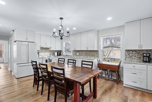 dining room featuring sink, light hardwood / wood-style floors, and a chandelier