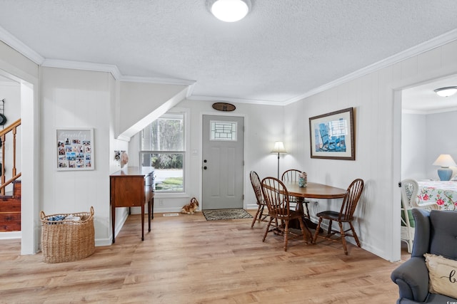 dining area featuring light wood-type flooring, a textured ceiling, and ornamental molding