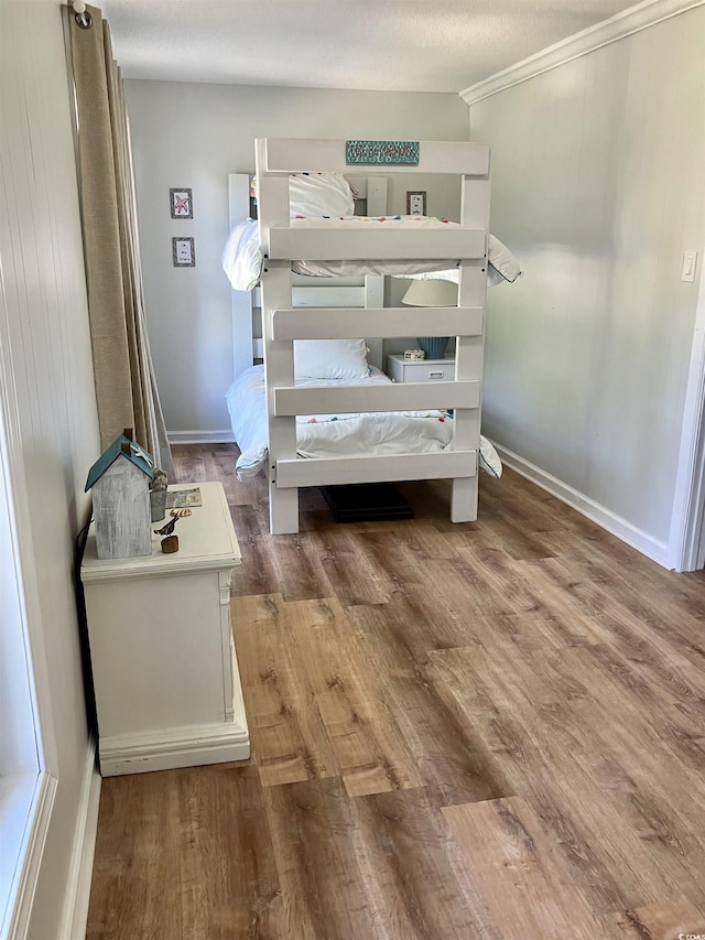 bedroom with hardwood / wood-style flooring, a textured ceiling, and crown molding