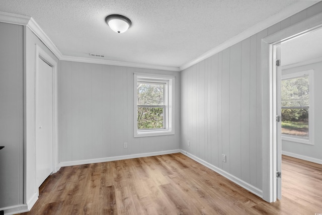 unfurnished bedroom featuring light hardwood / wood-style floors, a textured ceiling, and ornamental molding