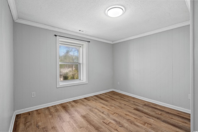 empty room featuring light hardwood / wood-style floors, a textured ceiling, and crown molding