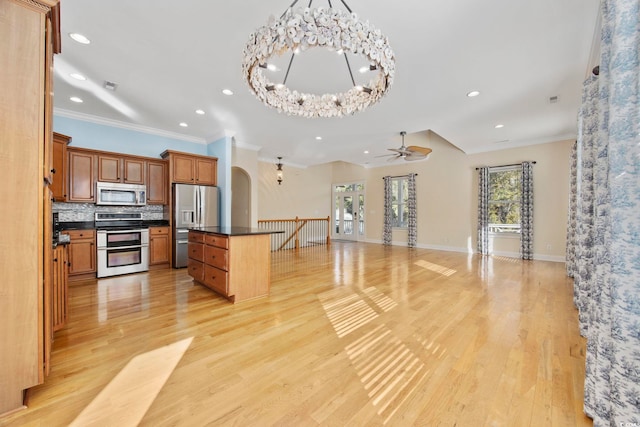 kitchen with appliances with stainless steel finishes, an inviting chandelier, tasteful backsplash, ornamental molding, and light wood-type flooring