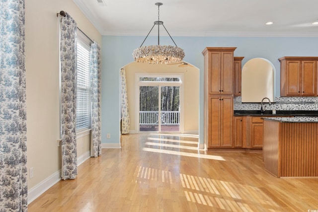 unfurnished dining area featuring sink, ornamental molding, and light hardwood / wood-style floors