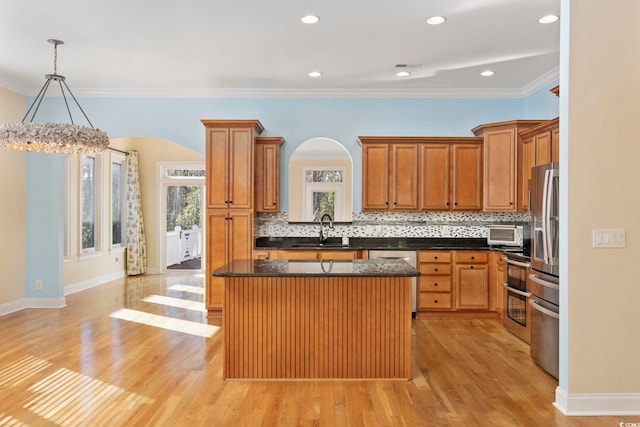 kitchen with sink, decorative backsplash, hanging light fixtures, a center island, and stainless steel appliances