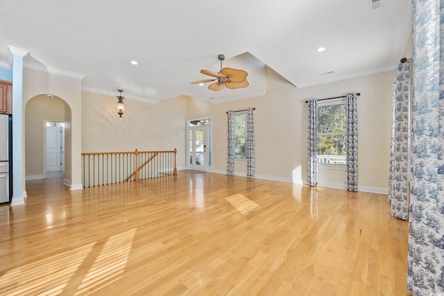 unfurnished living room with crown molding, a wealth of natural light, and light hardwood / wood-style flooring