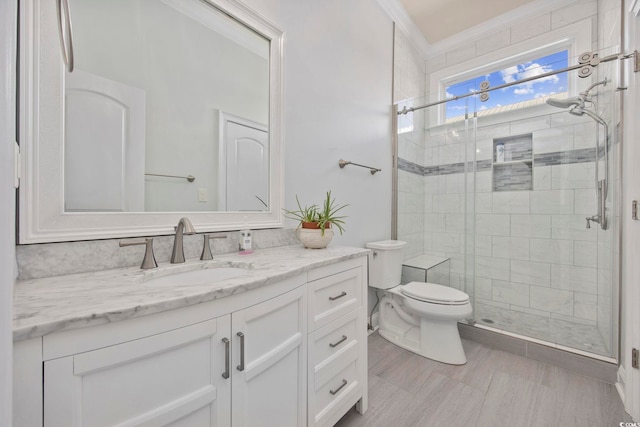 bathroom with vanity, crown molding, a shower with shower door, and toilet