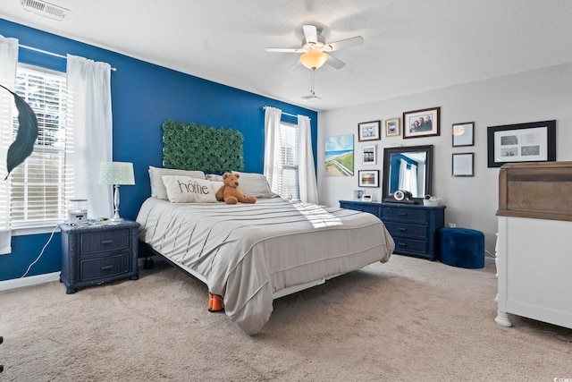 carpeted bedroom featuring ceiling fan, a textured ceiling, visible vents, and baseboards