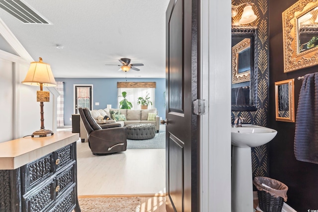 bathroom featuring a ceiling fan, visible vents, a sink, and wood finished floors