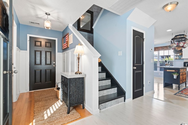 entryway with stairs, visible vents, and wood finished floors