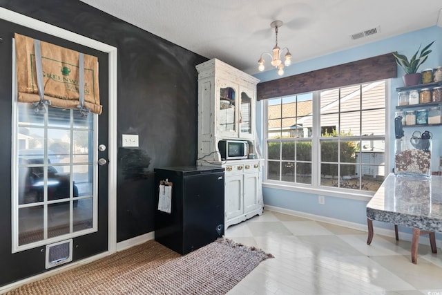 kitchen featuring hanging light fixtures, baseboards, visible vents, and a notable chandelier