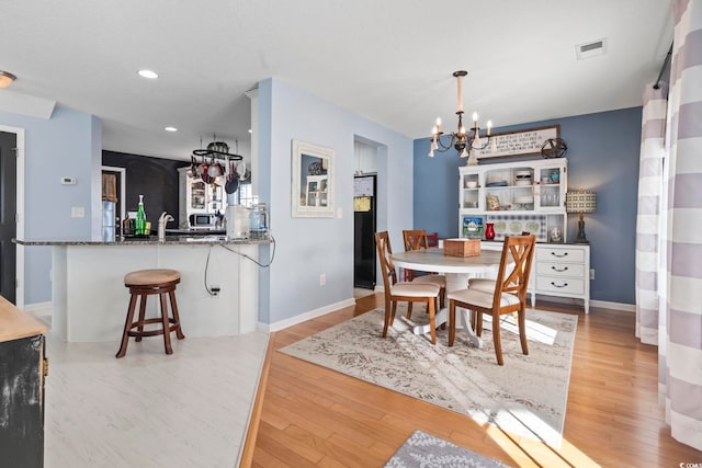 dining room with light wood-type flooring, an inviting chandelier, baseboards, and recessed lighting