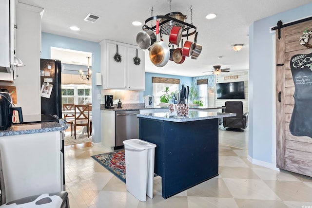 kitchen with a wealth of natural light, visible vents, stainless steel dishwasher, a barn door, and freestanding refrigerator