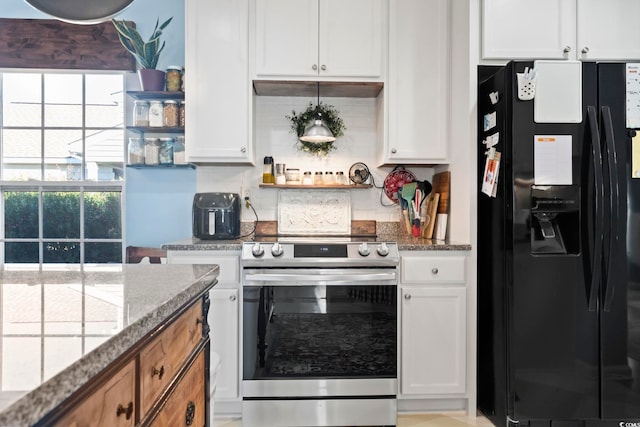 kitchen with stainless steel electric range oven, black fridge, stone countertops, and white cabinetry