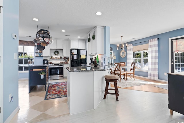 kitchen featuring plenty of natural light, a chandelier, black fridge, and stainless steel range with electric cooktop