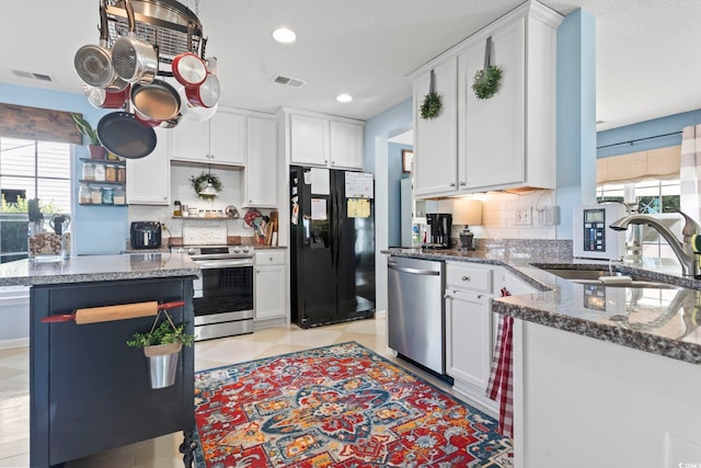 kitchen featuring stainless steel appliances, a sink, visible vents, white cabinets, and tasteful backsplash