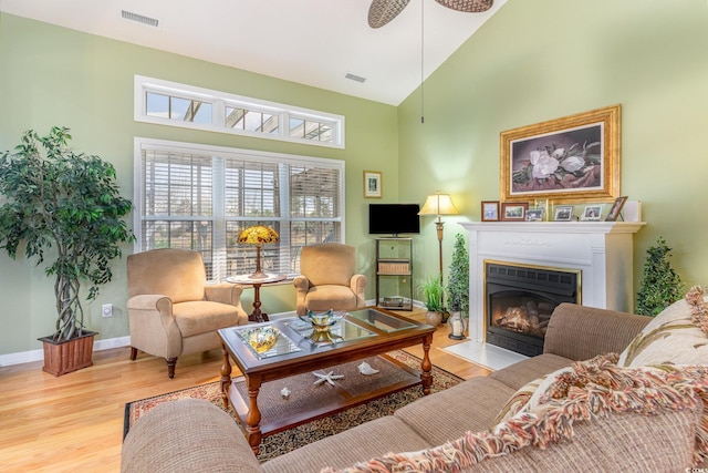 living room with ceiling fan, high vaulted ceiling, and light hardwood / wood-style flooring