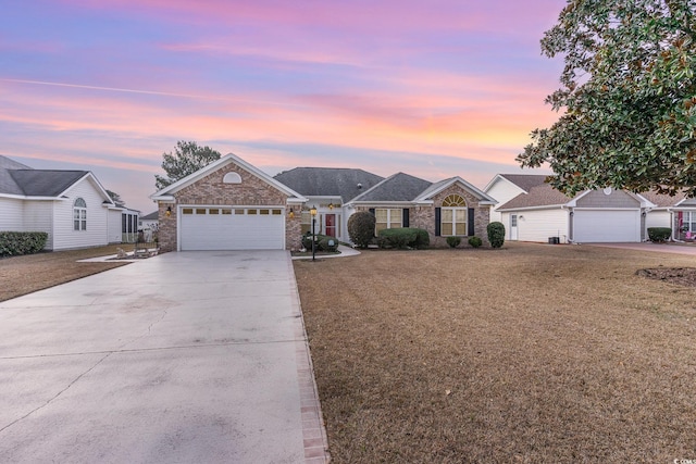 single story home featuring a garage and a lawn