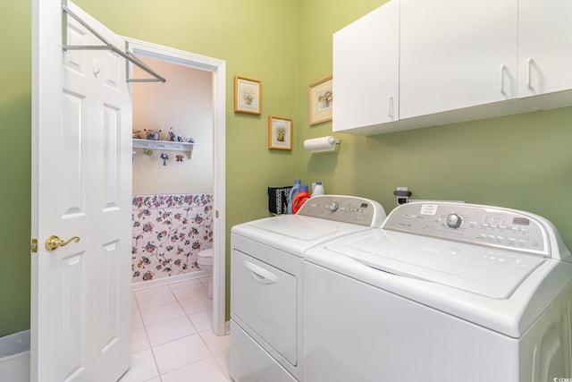 washroom featuring separate washer and dryer, light tile patterned floors, and cabinets