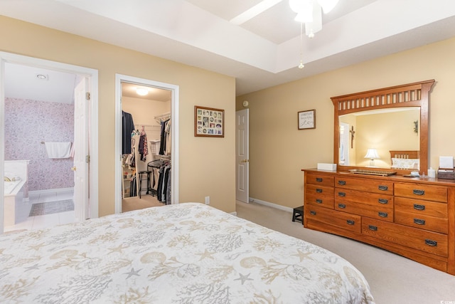 bedroom with a spacious closet, a closet, light colored carpet, ceiling fan, and connected bathroom