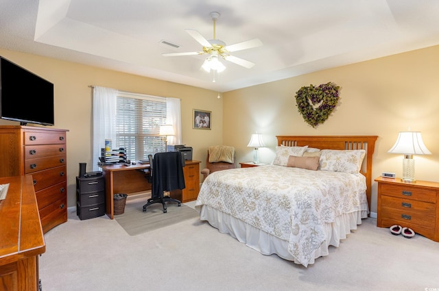 carpeted bedroom featuring a tray ceiling and ceiling fan