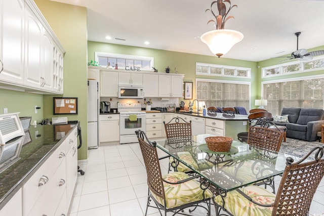 kitchen with white appliances, hanging light fixtures, light tile patterned floors, white cabinets, and sink