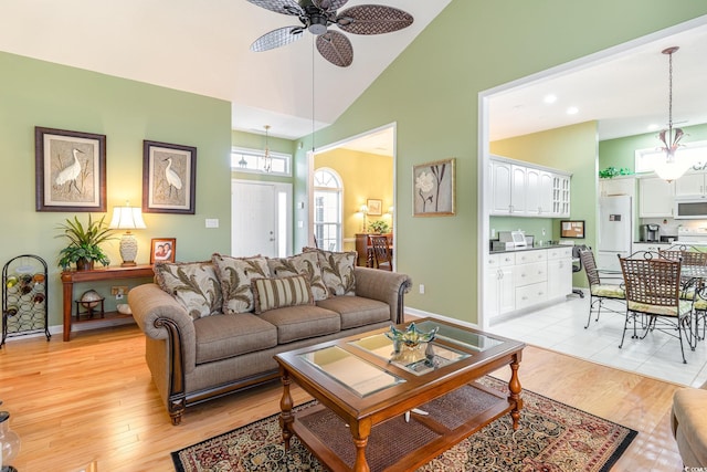 living room with light hardwood / wood-style floors, high vaulted ceiling, and ceiling fan