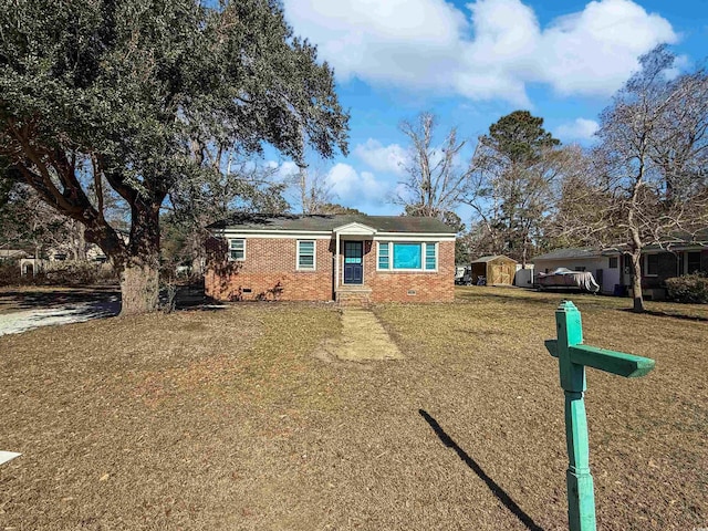 ranch-style house featuring a front lawn and a shed