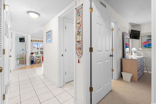 hall featuring light tile patterned floors and a textured ceiling