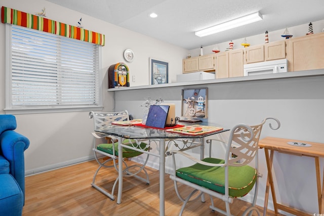 dining space featuring light hardwood / wood-style floors and a textured ceiling