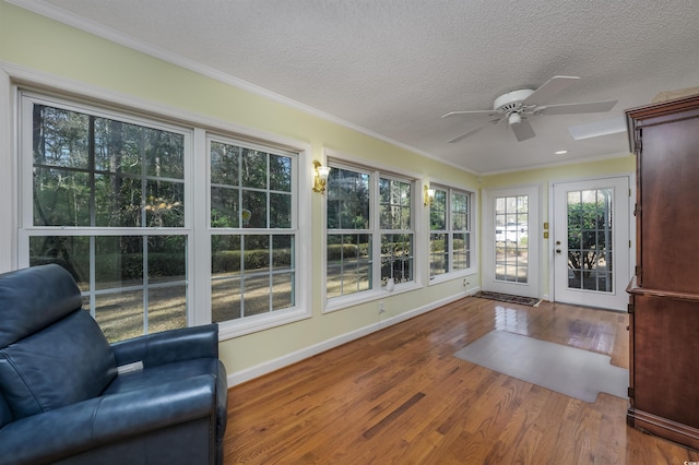 unfurnished sunroom featuring crown molding, wood finished floors, baseboards, and a textured ceiling