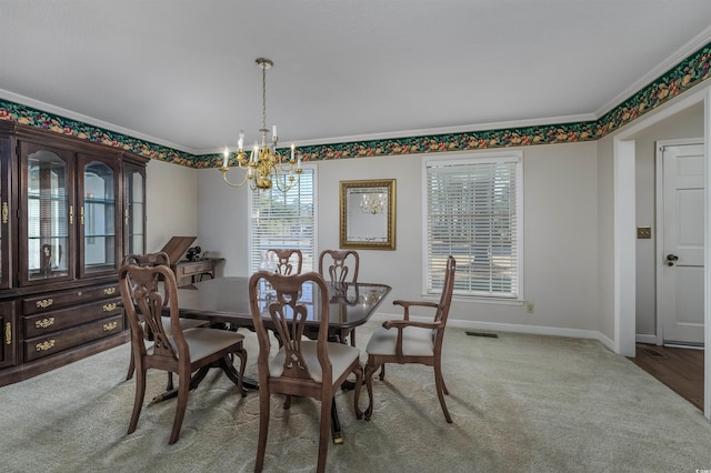 carpeted dining room featuring ornamental molding, baseboards, visible vents, and a chandelier