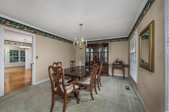 carpeted dining area featuring visible vents, baseboards, a chandelier, and crown molding